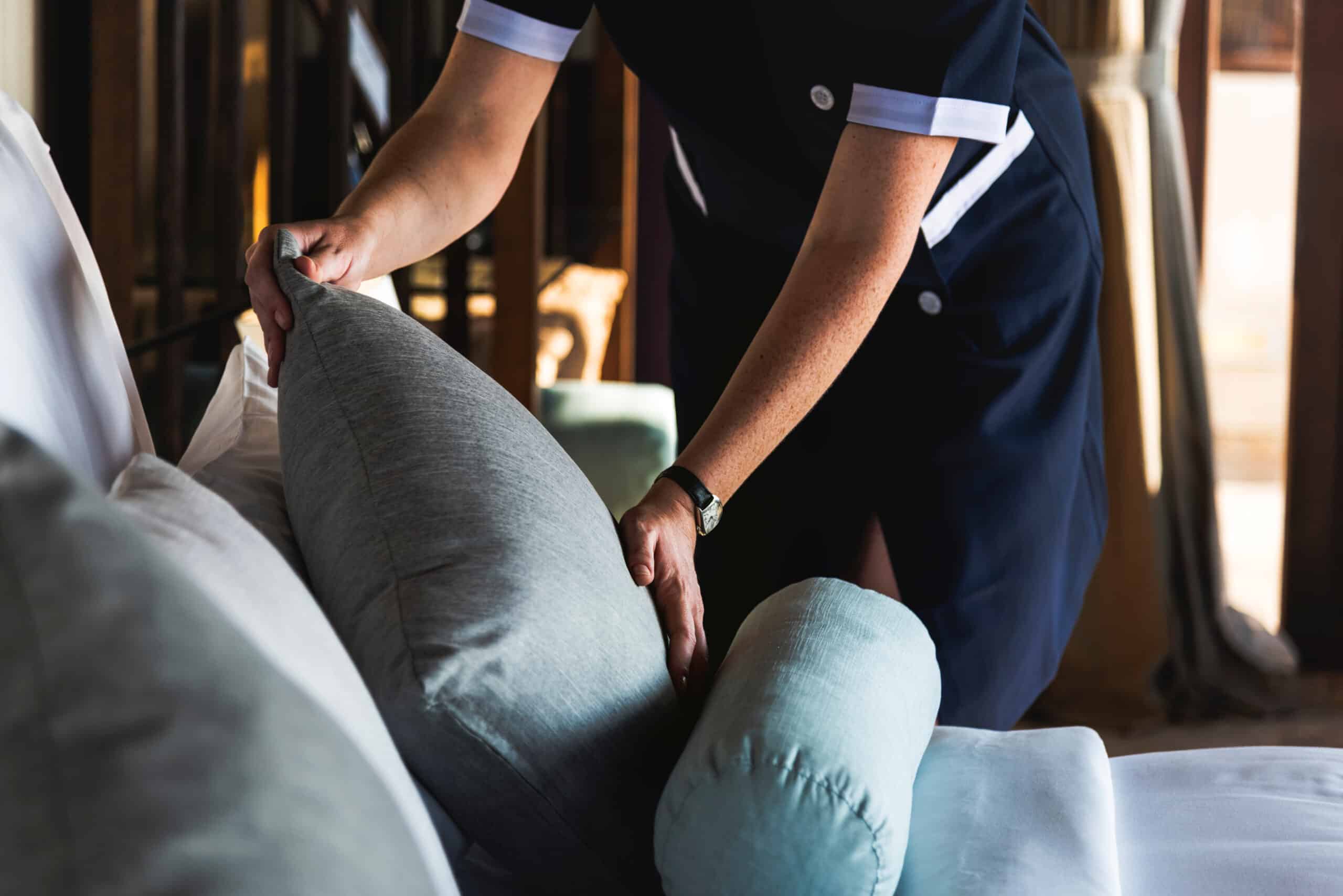 An employee at The 501 adjusting a pillow on a bed, as a apart of independent living services