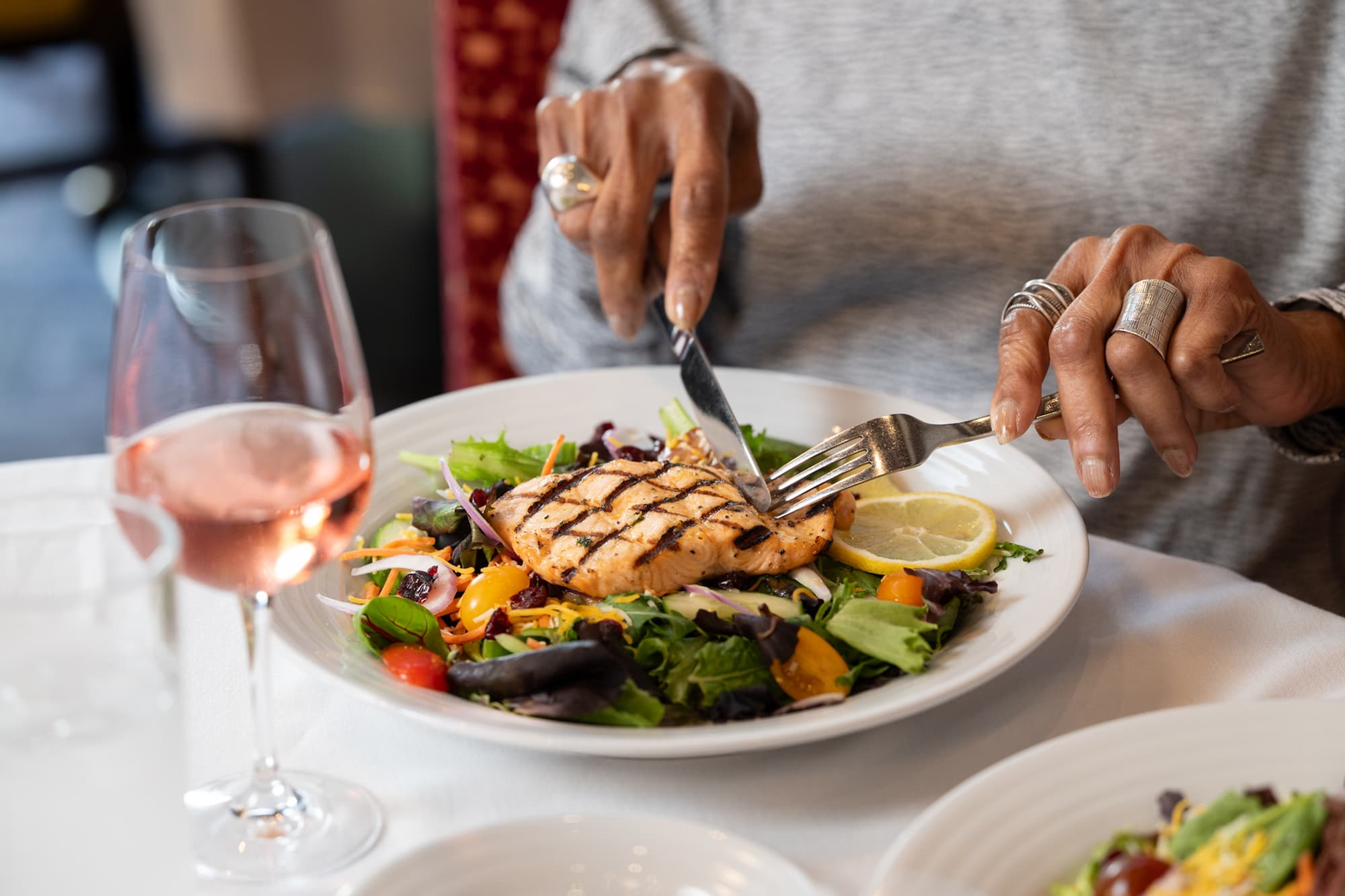 a close up of a dinner plate complete with varied greens and a seared fish filet with lemon